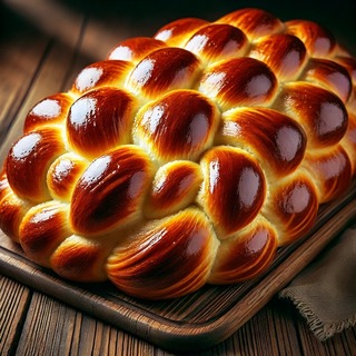 DALLEE 2024-10-14 01.09.07 - A beautifully braided challah bread, with a shiny golden-brown crust, slightly glossy from egg wash. The loaf is intricately woven, showcasing its sof.jpg