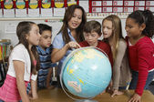 depositphotos_21965821-Teacher-explaining-globe-to-students.jpg