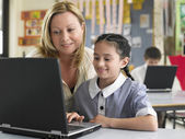 depositphotos_33834391-Teacher-helping-student-with-laptop.jpg